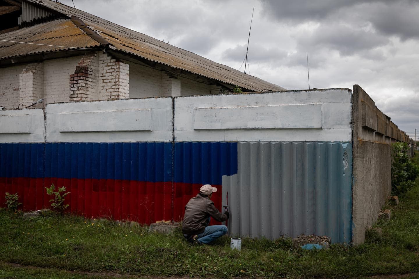 Ілюстративне фото. Чоловік зафарбовує російський прапор у нещодавно звільненому селі