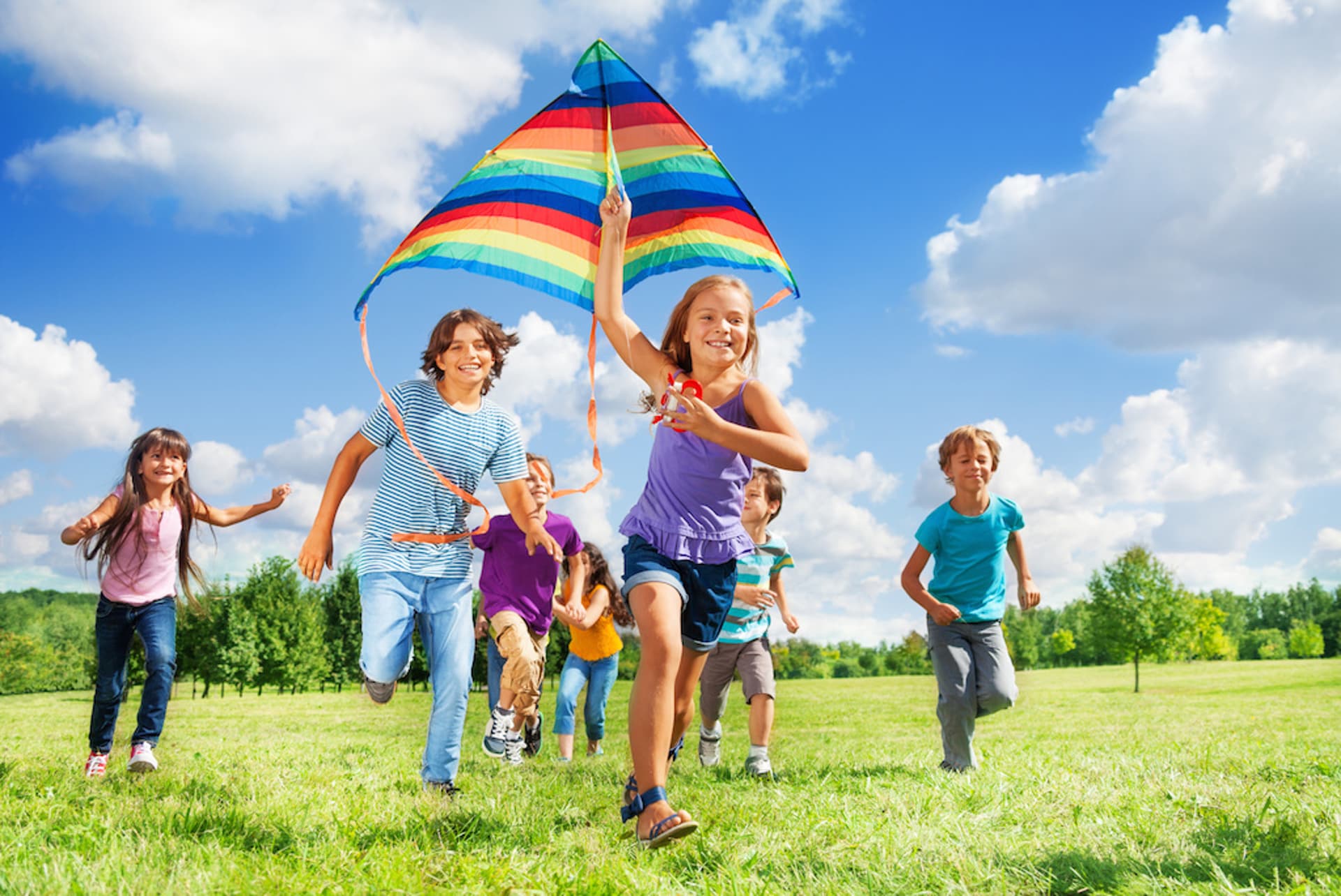 Many happy active kids boys and girls run with kite in the park