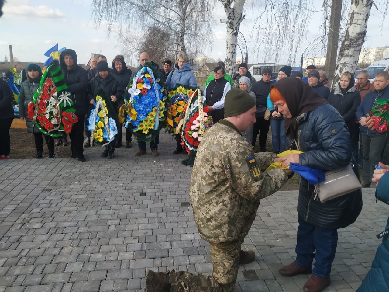 Матері воїна передають державний прапор на могилі сина