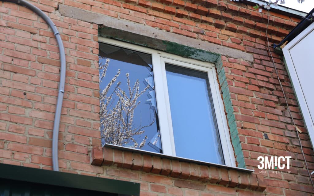 Квітуче дерево відбивається у пошкодженому унаслідок обстрілу вікні